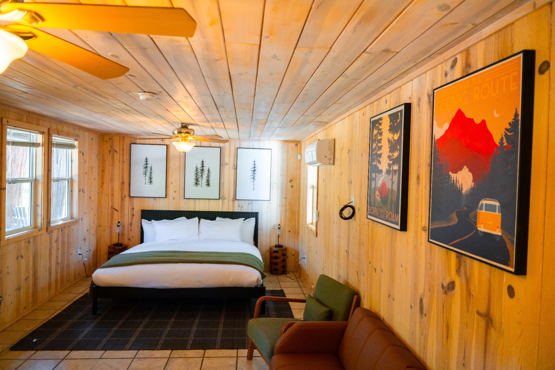 Suite interior with king bed, seating, and travel posters