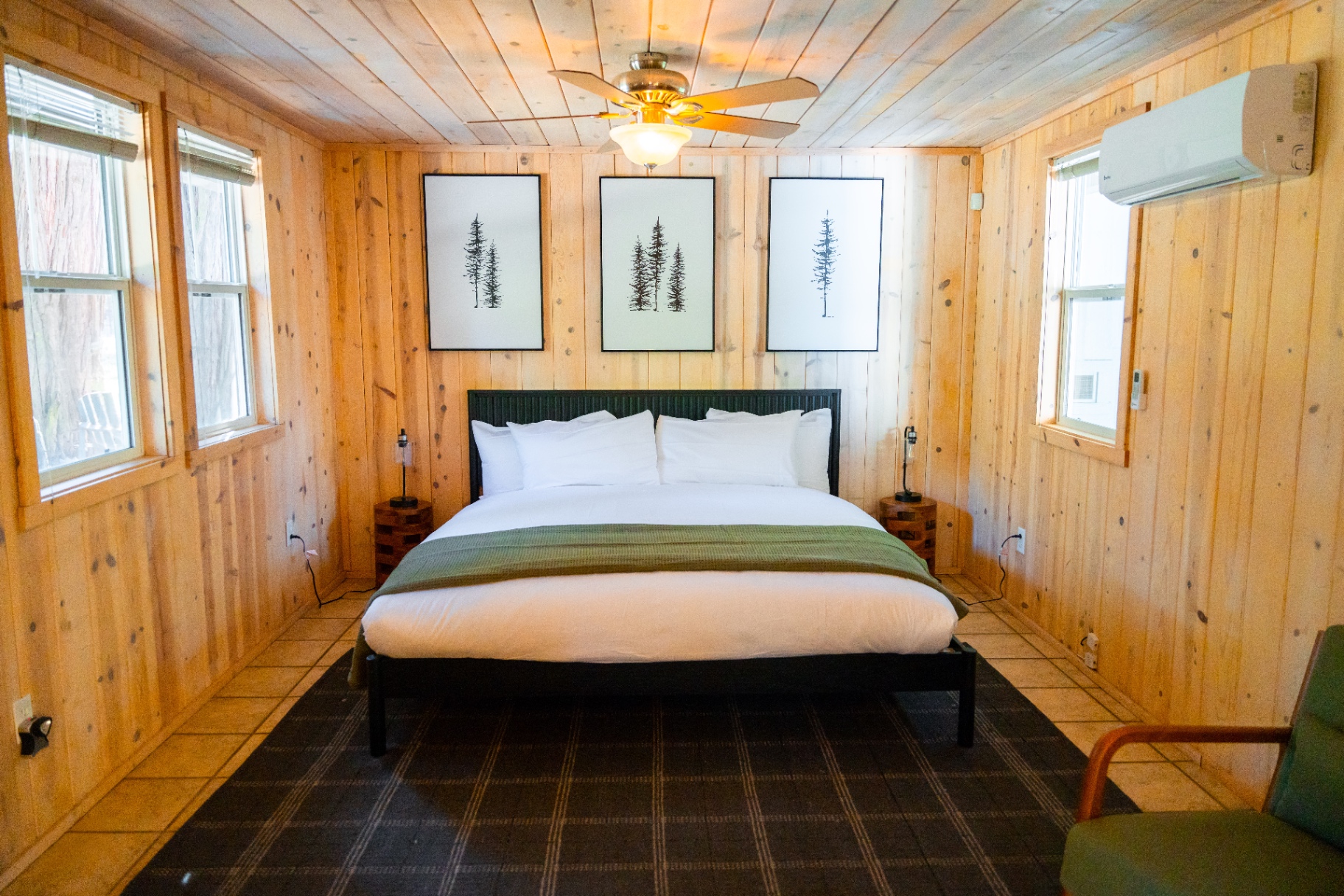 King bed with framed pine art in a wood-paneled suite