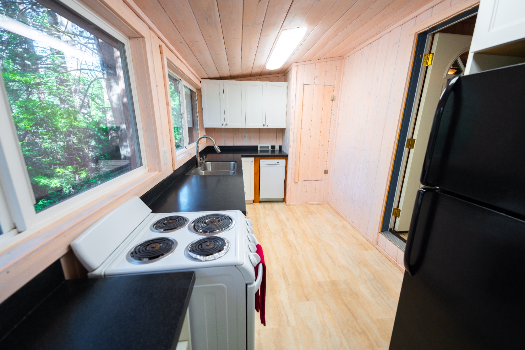 Full kitchen with stove, sink, and forest view